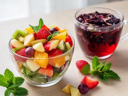 Taça de salada de fruta da época acompanhada por uma infusão detox de hibisco e menta